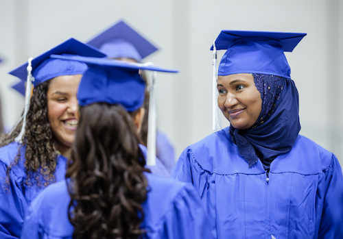 Photo of a graduate smiling at another graduate.