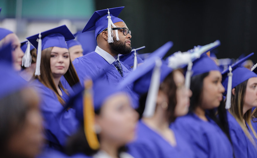 Crowd of graduates sitting with two standing.