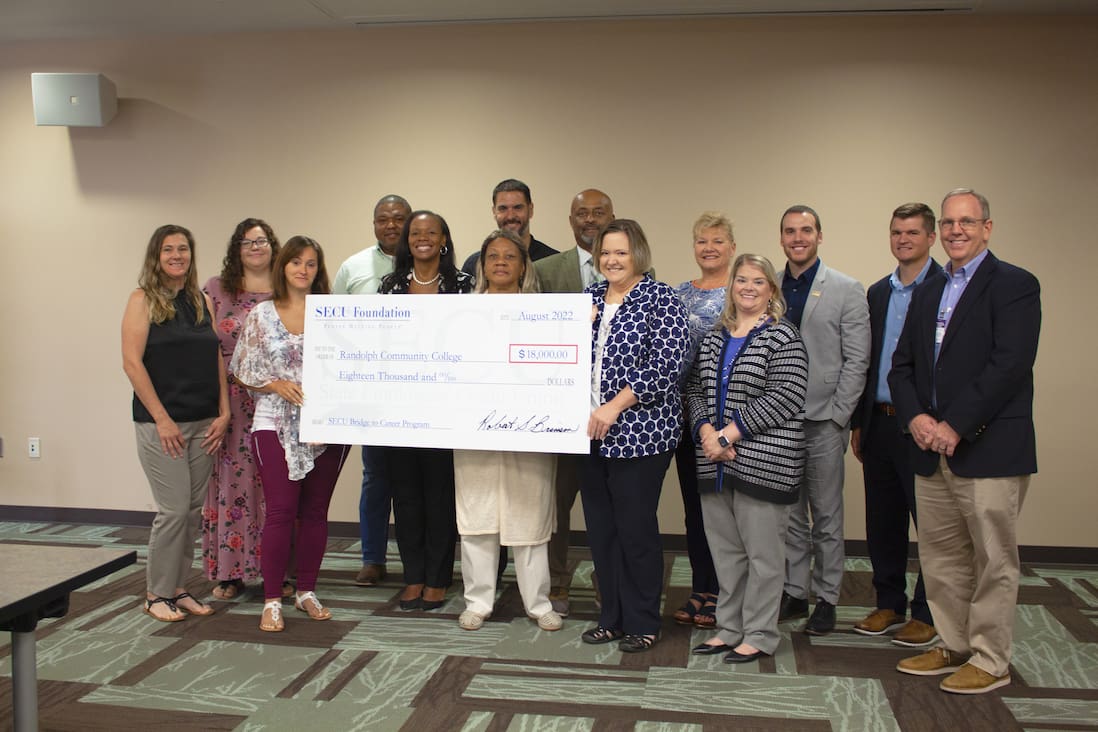 Members of the State Employees' Credit Union (SECU), along with Randolph Community College staff and students, celebrate the SECU's scholarship donation to the College during a ceremony Aug. 25 in the JB and Claire Davis Corporate Training Center on the Asheboro Campus.