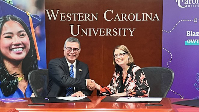 Photo of two people sitting at a table and shaking hands.