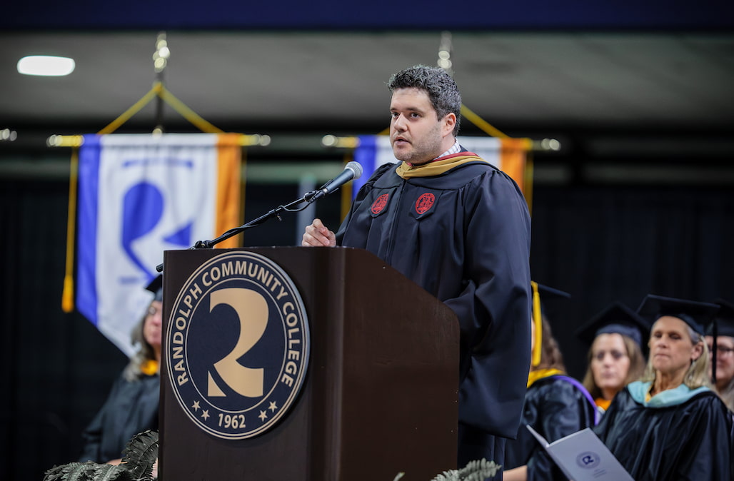 Photo of a person standing at a podium and giving a graduation speech.
