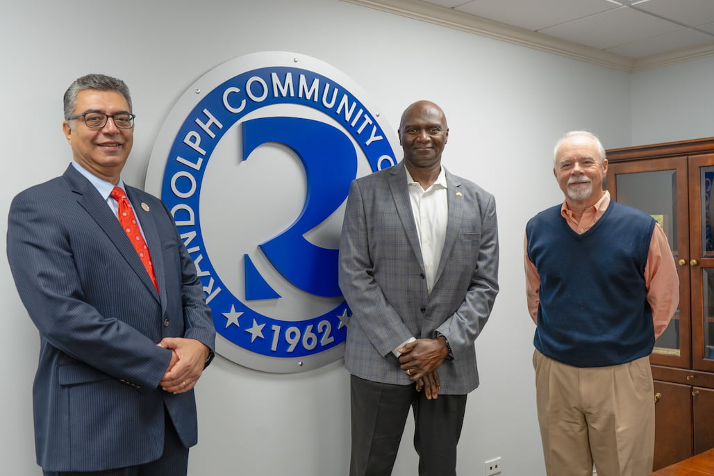 Photo of three people standing by the Randolph Community College seal.