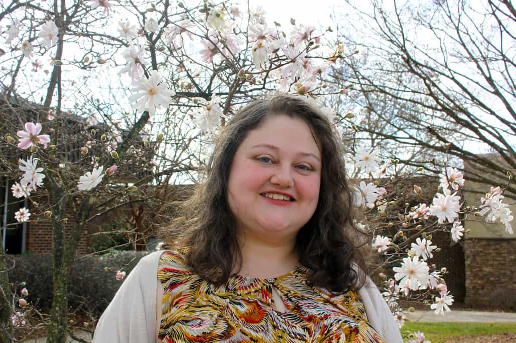 Photo of a woman standing in front of a flowering tree.