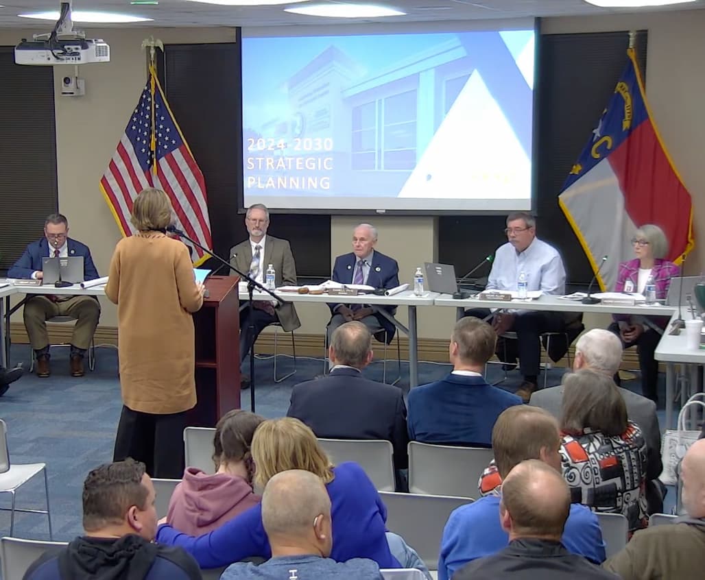 Photo of a Board of Commissioners listening to someone give a presentation at a podium.