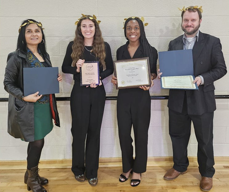 Photo of four people standing and holding awards.