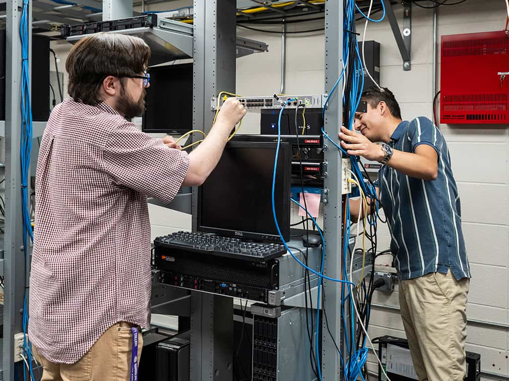 Photo of two people working on a server.