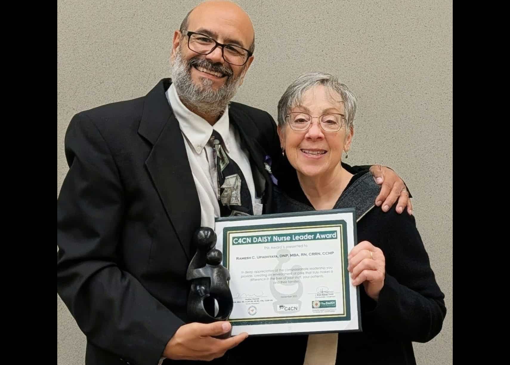 Photo of two people posing for a photo while holding an award.