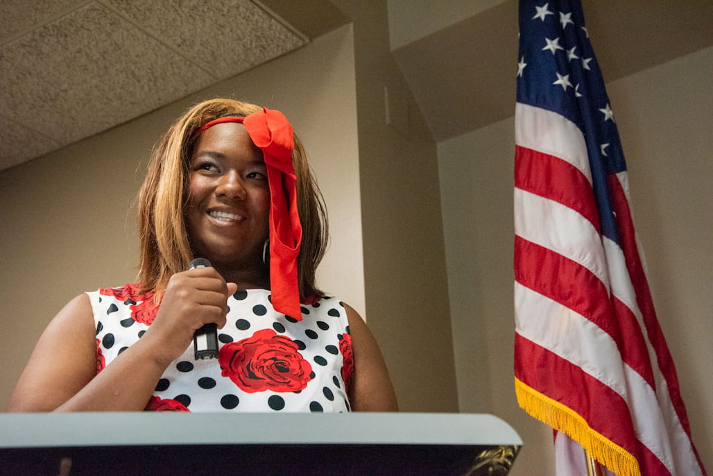 Photo of a person speaking at a podium with the American flag in the background.