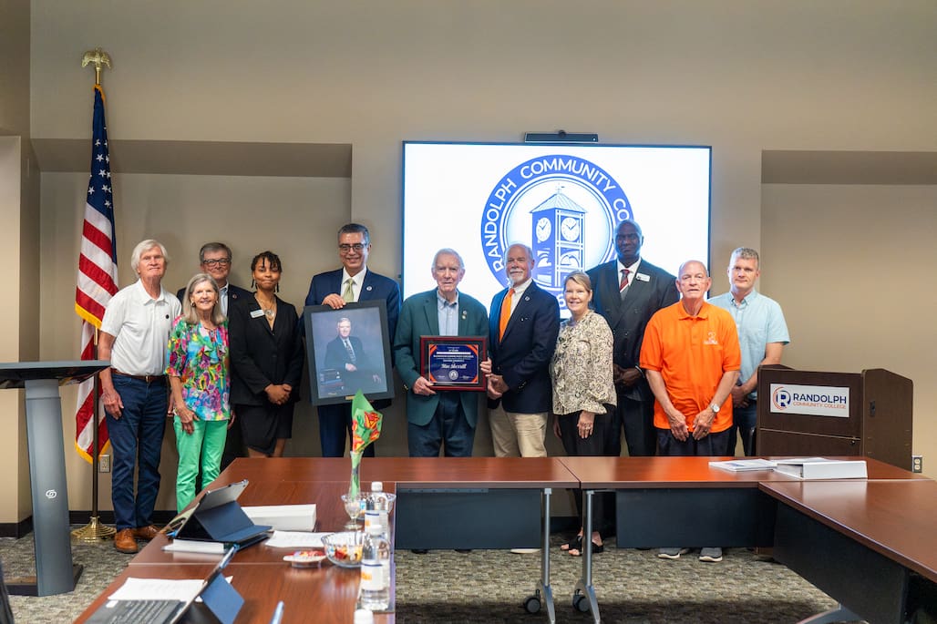 Photo of a group of people standing for a photo in the Martha Luck Comer Foundation Conference Center at Randolph Community College.