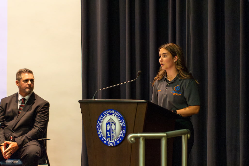 Photo of a person giving a speech at a podium in the R. Alton Cox Learning Resources Center at Randolph Community College.