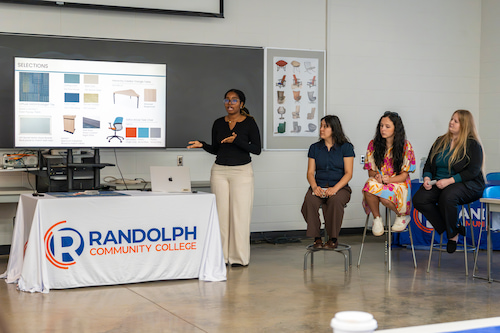 Photo of a student presenting a proposal while their fellow students look on.