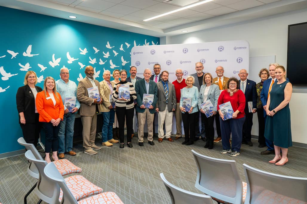 Photo of a large group of people standing in room 103 of the Allied Health Center.