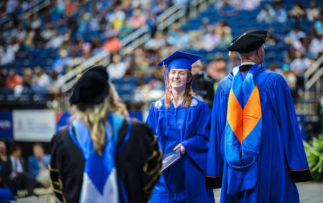 An RCC graduate smiles as they walk across the stage at the 2026 Commencement Ceremony at First Horizon Coliseum.