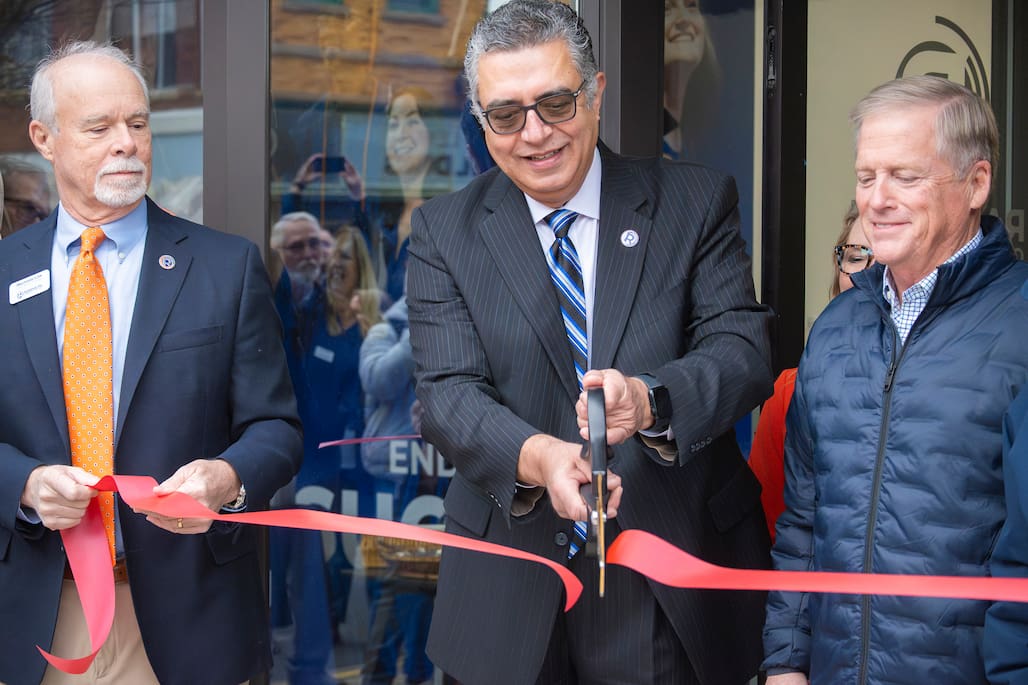 Photo of three people with one cutting a ribbon.