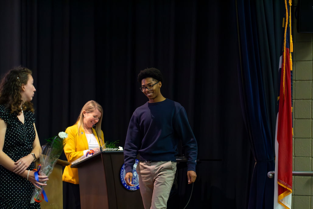 Photo of a person walking across a stage.