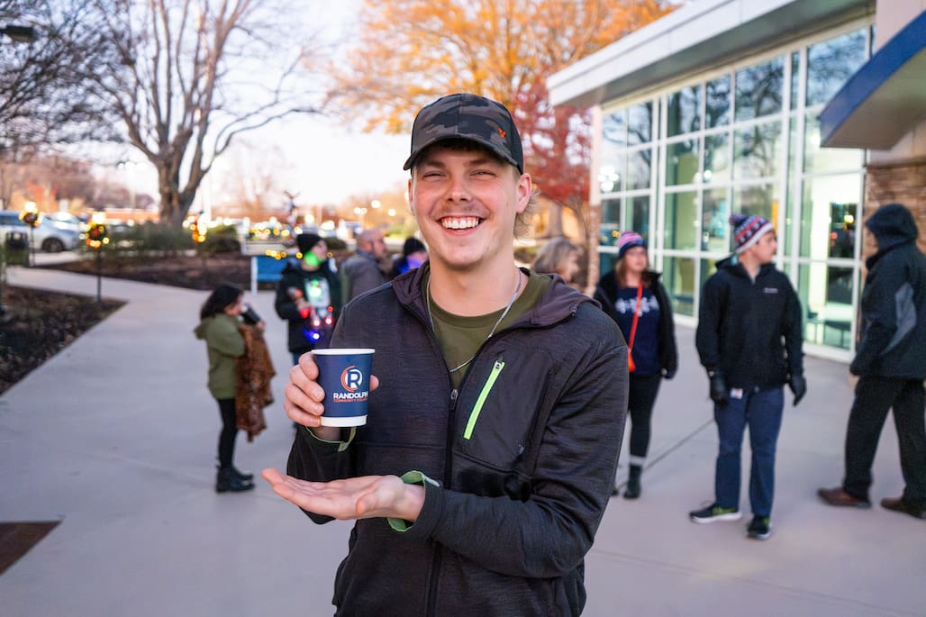 Photo of Randolph Community College student Jordan Deaton smiling and holding a cup of hot cocoa in The Plaza.